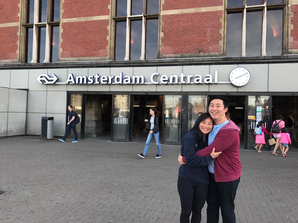 Kelly and Eric hugging in front of a sign for the Amsterdam Centraal station